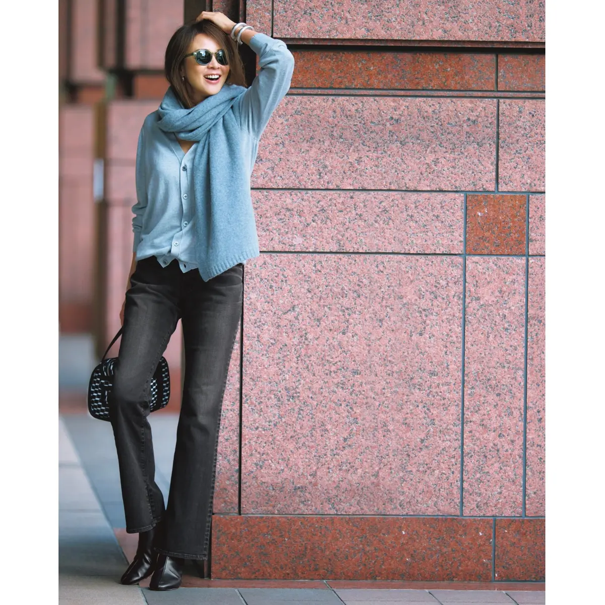 ライトブルーのVネックカーディガンに近いトーンのニットマフラーを首元に巻き、ブラックデニムのスリムパンツを合わせたコーディネート　モデル・SHIHO