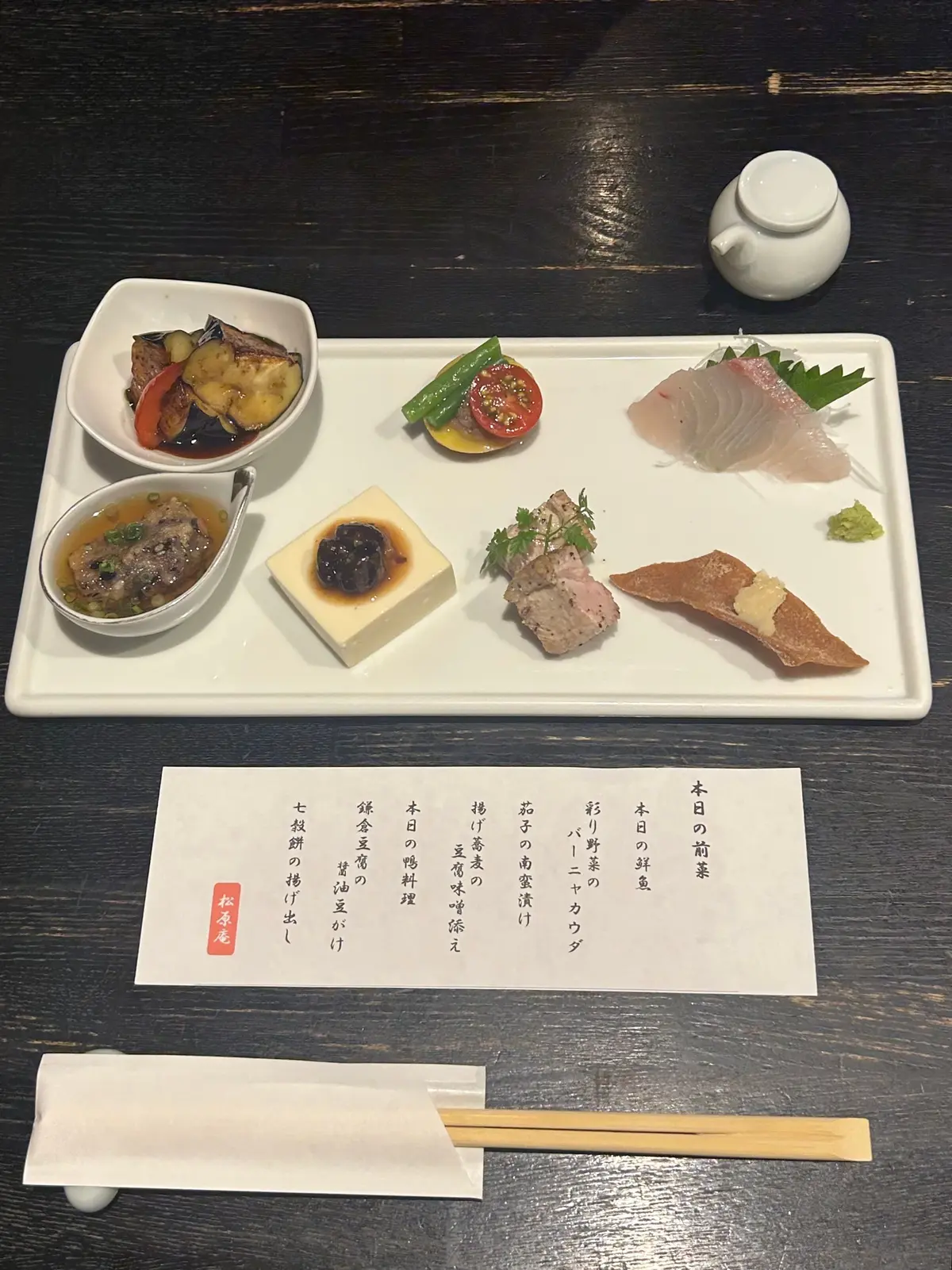 蕎麦コース（松原庵）前菜。左上には茶色い団子のようなものと黄色い汁、中央には緑色の葉物とピンク色の肉、右側には薄切り肉とソース、そして小さな白い器に入った料理が並んでいる。