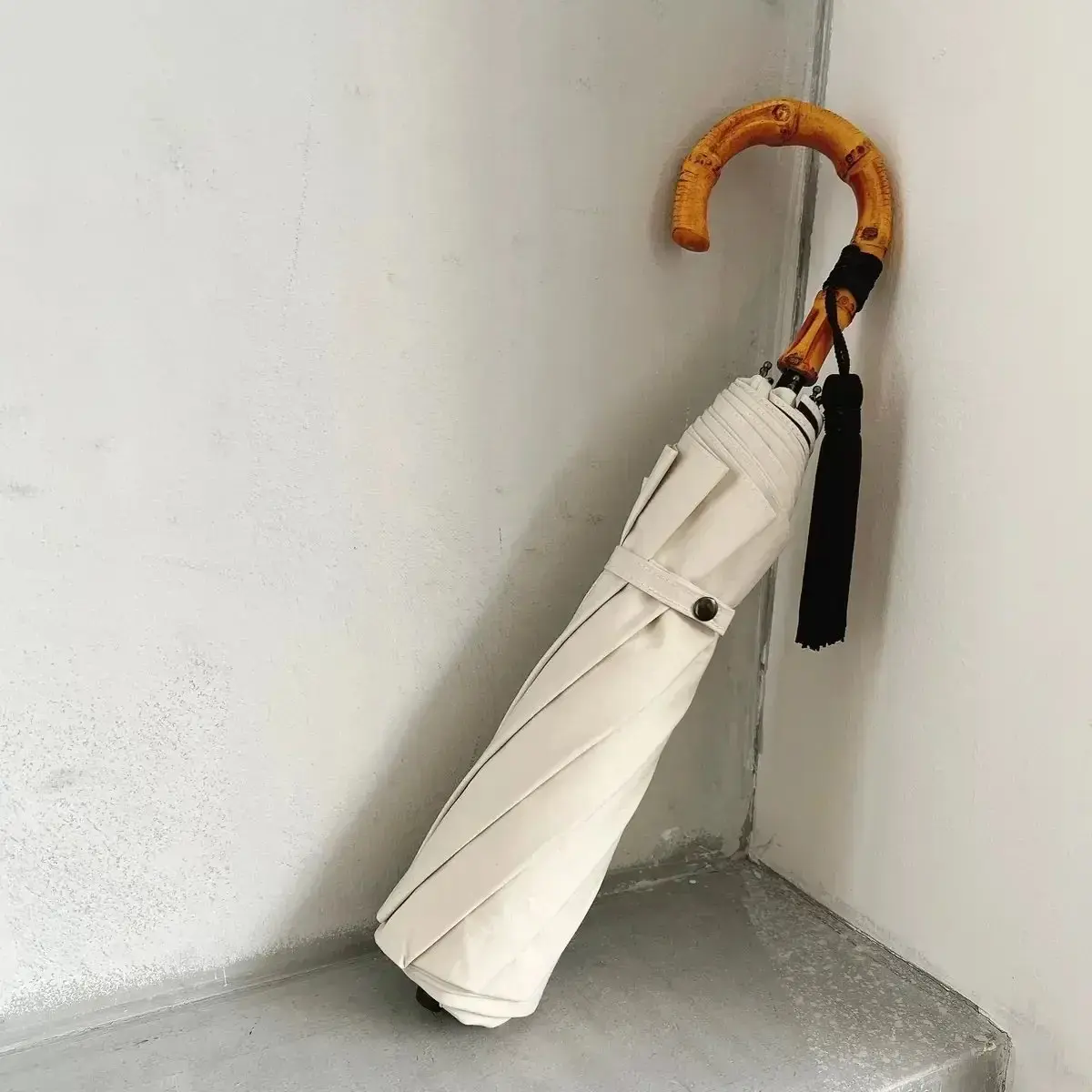 白い傘が木製の柄で壁に立てかけてある
