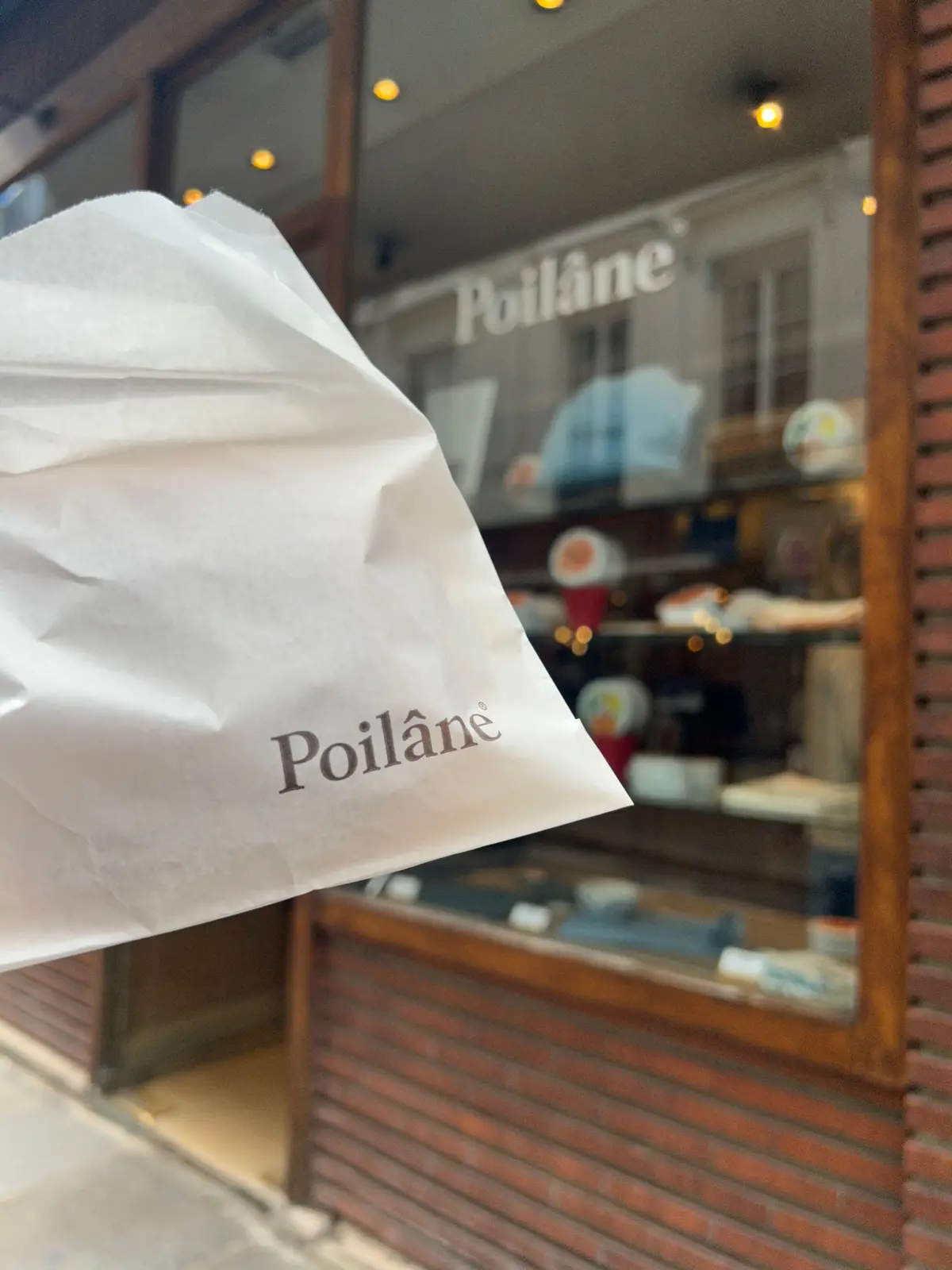 Poilâneの紙袋が店前のガラス窓に映る