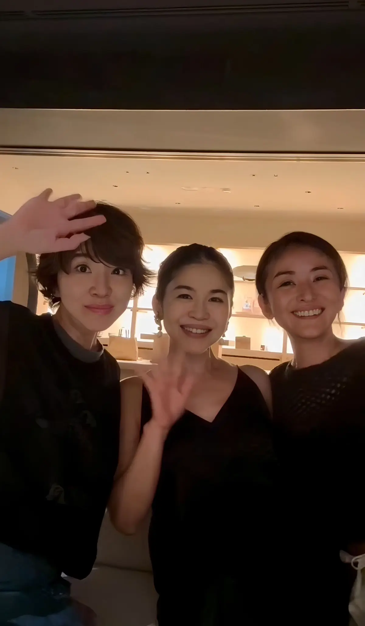 3人並んで笑顔で写るセルフィー写真。左は手を頭に当てて、中央と右は手を振っている。背景は明るい内装のレストランのよう。