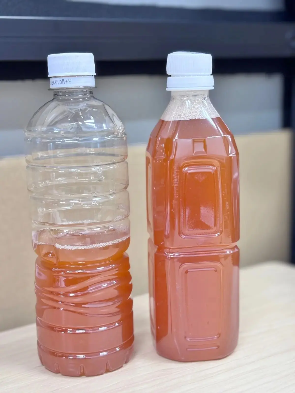 透明なペットボトルと茶色い液体が入ったペットボトルが並んでいる。透明なボトルには少量の茶色い液体があり、右のボトルには満遍なく茶色い液体が充填されている。