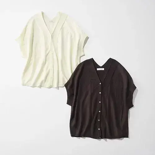 オフホワイトと黒の、Vネックのボタンダウンシャツ2枚。ゆったりとしたシルエットで、短い袖口が特徴。白いシャツは上部が開いており、黒いシャツは平らな状態。