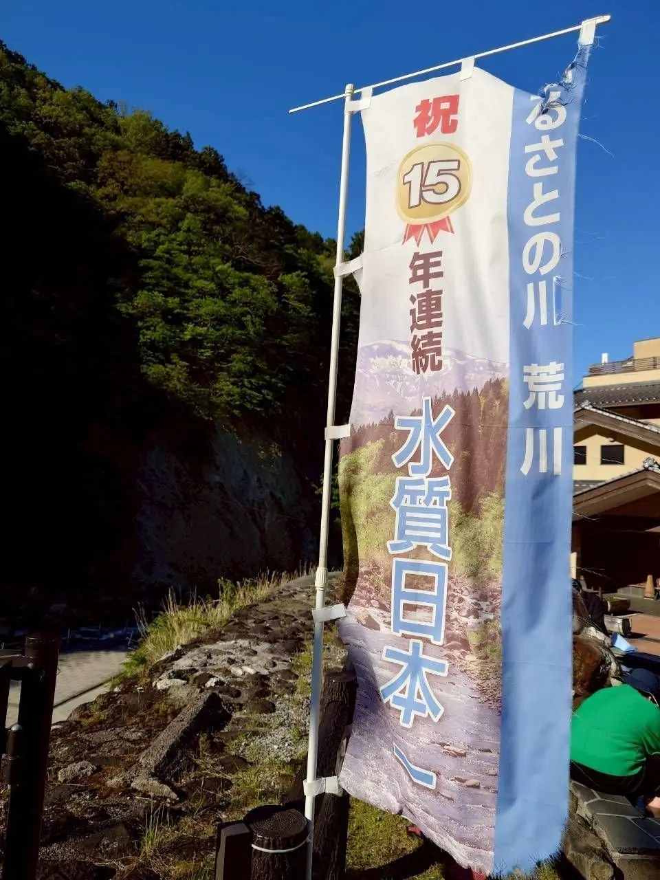 「15周年記念 水質日本一」とのぼりに書かれ、川の風景が描かれている