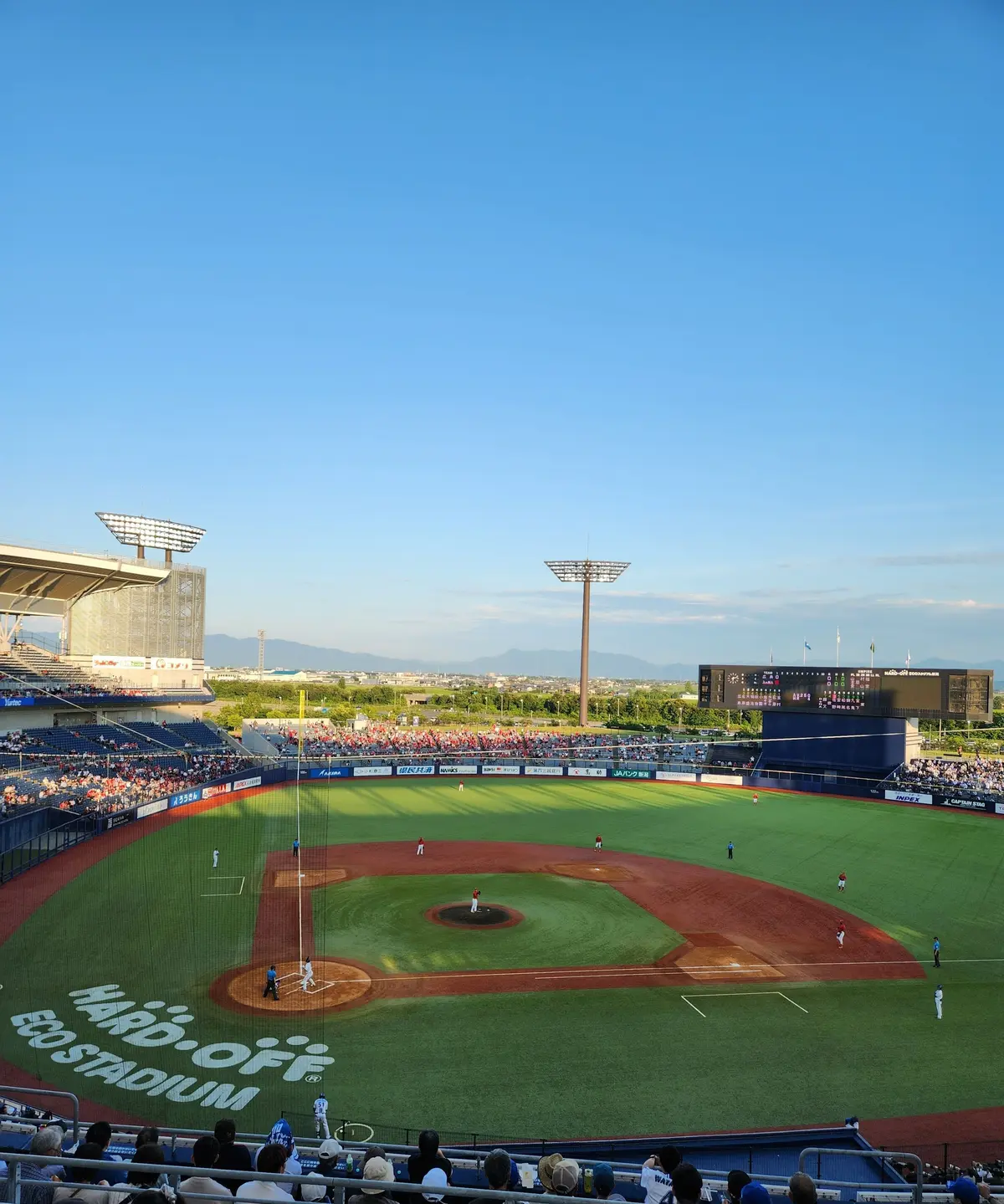 野球場に選手が配置され、観客が座っている。緑のフィールドに「ECO STADIUM」と書かれ、巨大なスクリーンが設置されている。