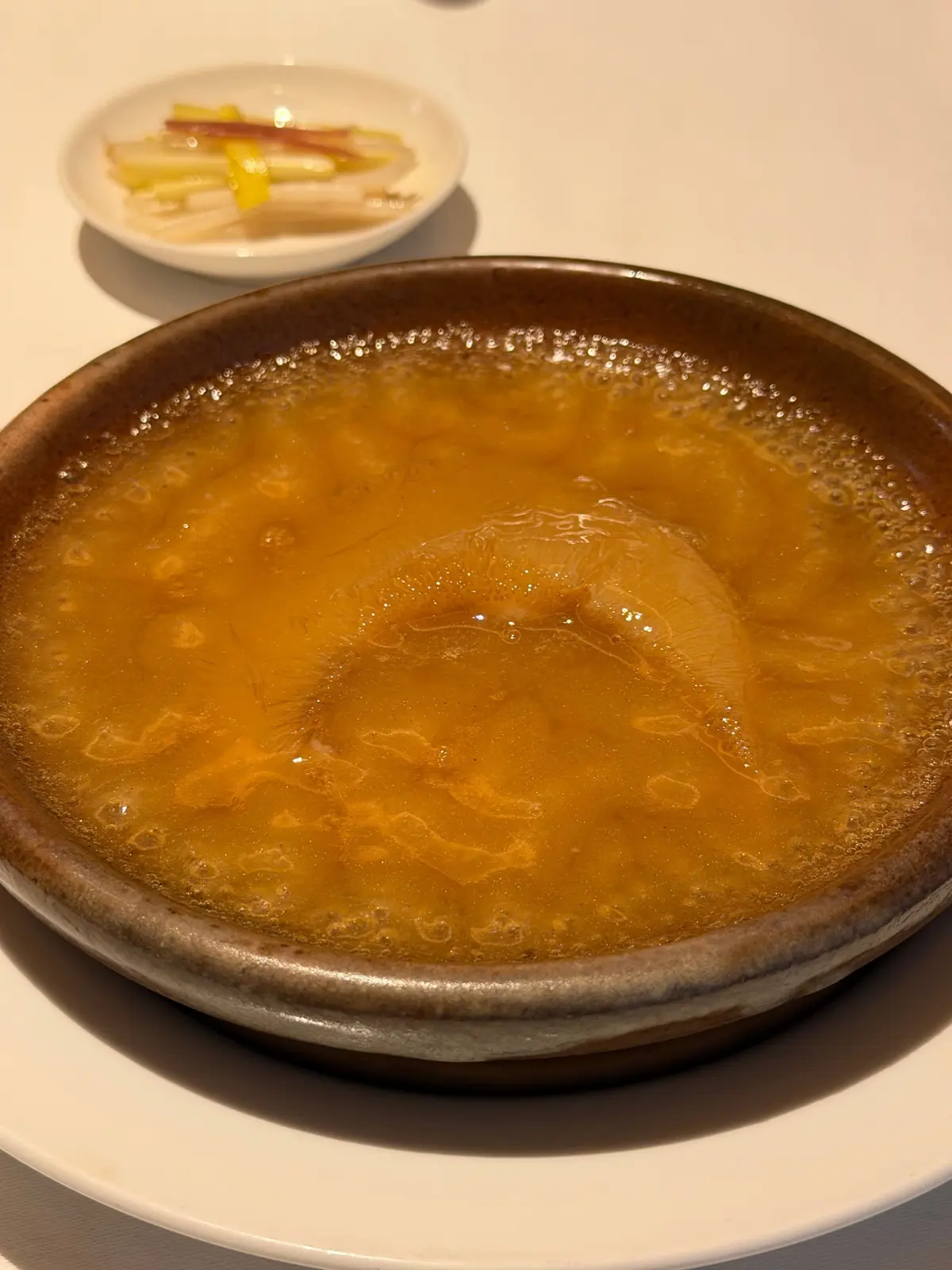 茶色いゼリーが器に入ったデザートで、小さな白い皿には野菜の盛り合わせが添えられている