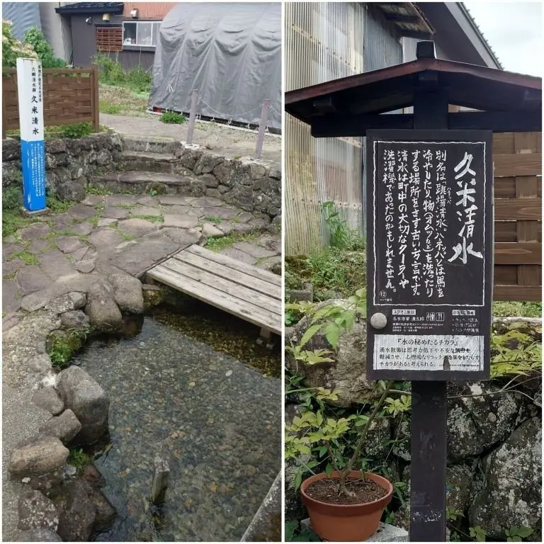 古民家風の建物前にある石橋と水路。水路は石積みで組まれ、橋は木製。建物には日本語の案内板が設置されている。背景には白いテントが見える。