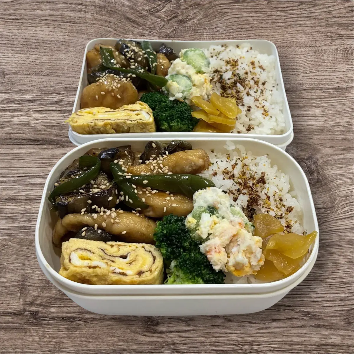 白い容器に、米、ブロッコリー、卵料理、野菜の盛り合わせが配置された二段弁当