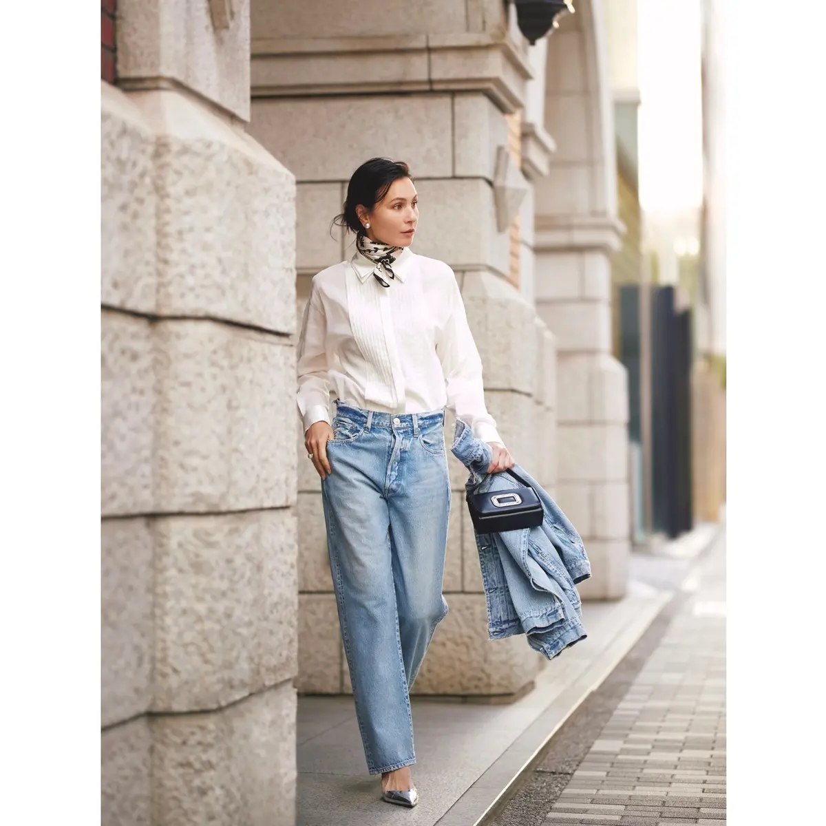 白シャツにライトブルーデニムのパンツを合わせ、手に同じデニムのジャケットを持ったスタイル　モデル・田沢美亜