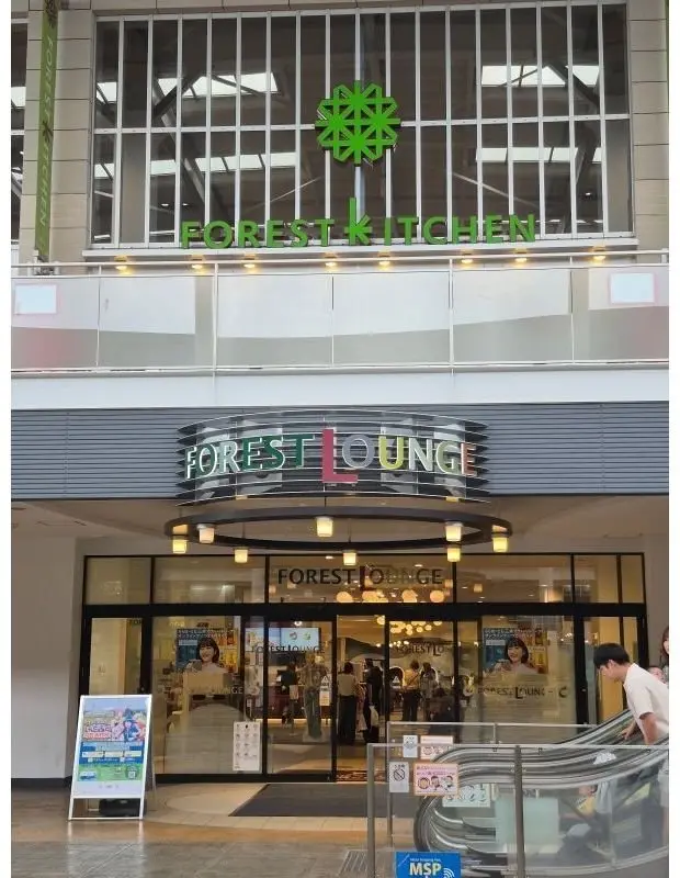 ショッピングモール内にある「FOREST KITCHEN」と「FOREST LOUNGE」の入り口。
緑色のロゴと、ガラス張りの入り口が特徴的。エスカレーターが右側に設置されている。