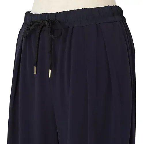 濃紺色のワイドパンツ。ウエストはゴムで、黒いドローコードが通っている。裾に向かって緩やかに広がったシルエット。
