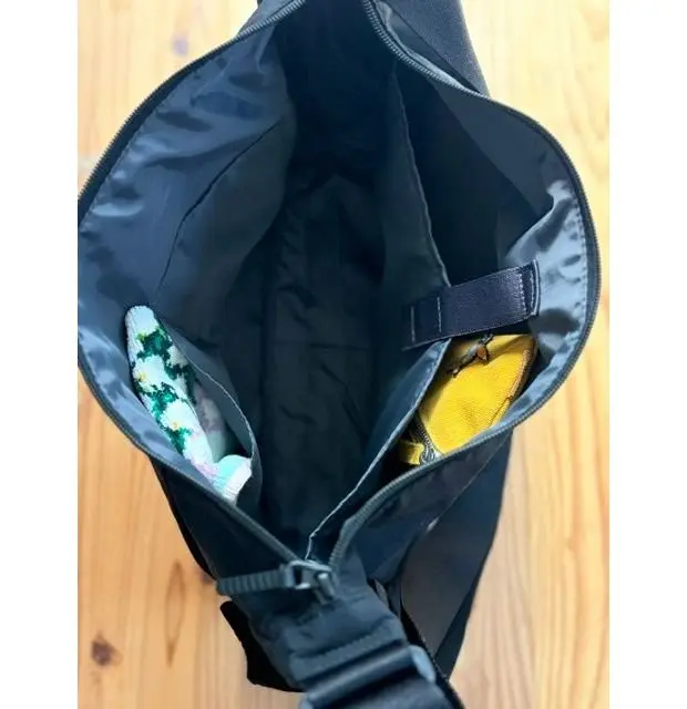 黒いバッグの中身。左側にはカラフルな靴下数足、右側には黄色い手袋が収まっている。バッグ内側は黒色で、上部にはジッパー付きの仕切りがある。