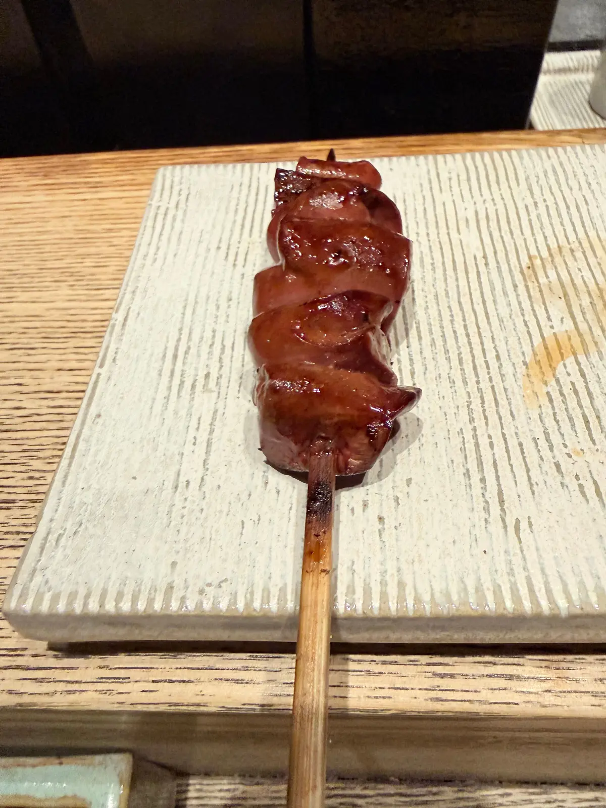 焼き鳥の串焼き、木の串に刺さった焼き色のある肉が白いプレートに置かれている