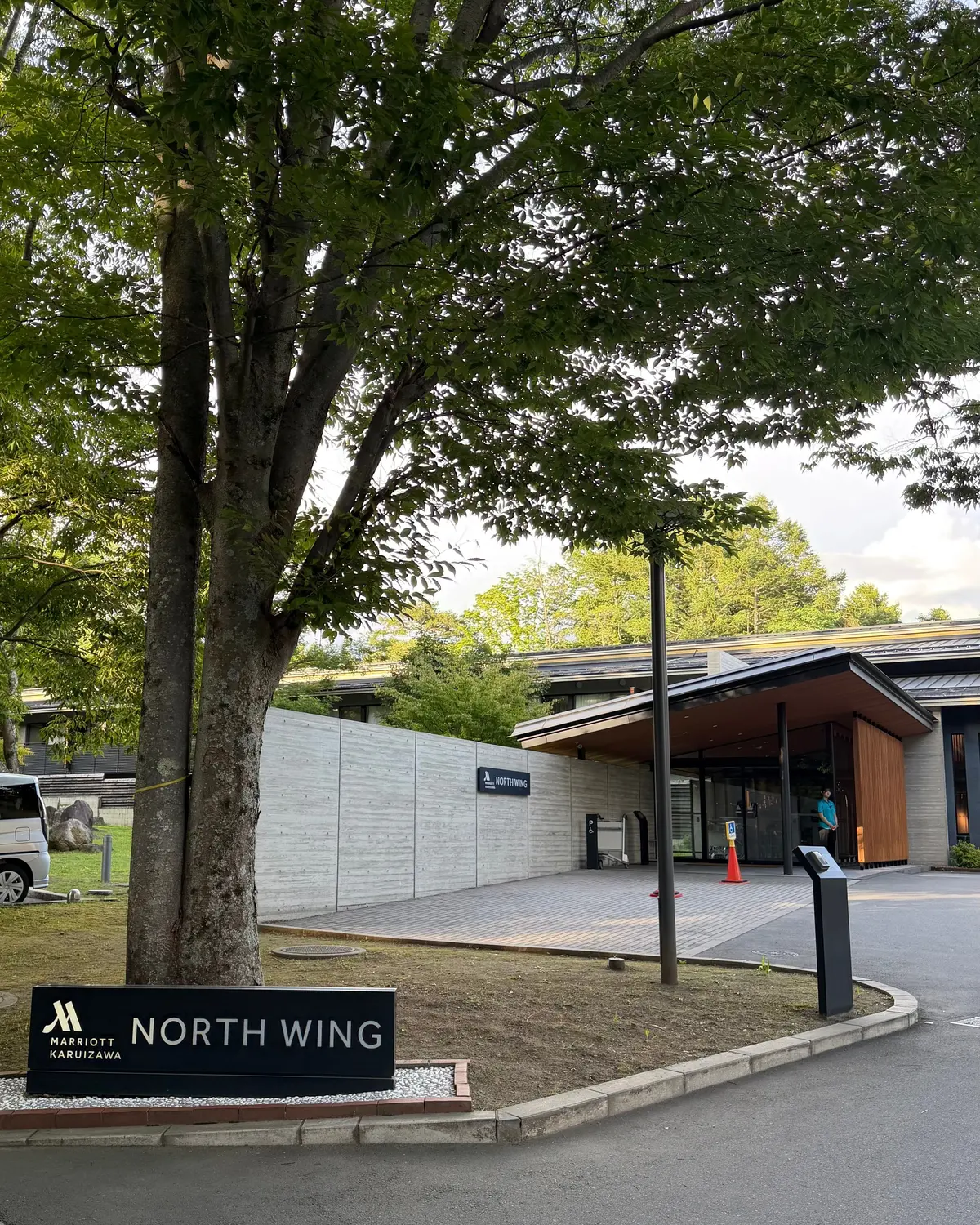 緑豊かな木陰に、マリオット カルizawaの北館の入り口が見える。木製の看板には「NORTH WING」の文字が記されている。