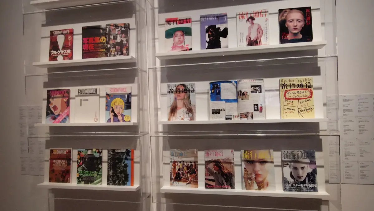 多数の雑誌が透明な棚に整列し、表紙に様々な人物の写真や日本語のタイトルが並んでいる。