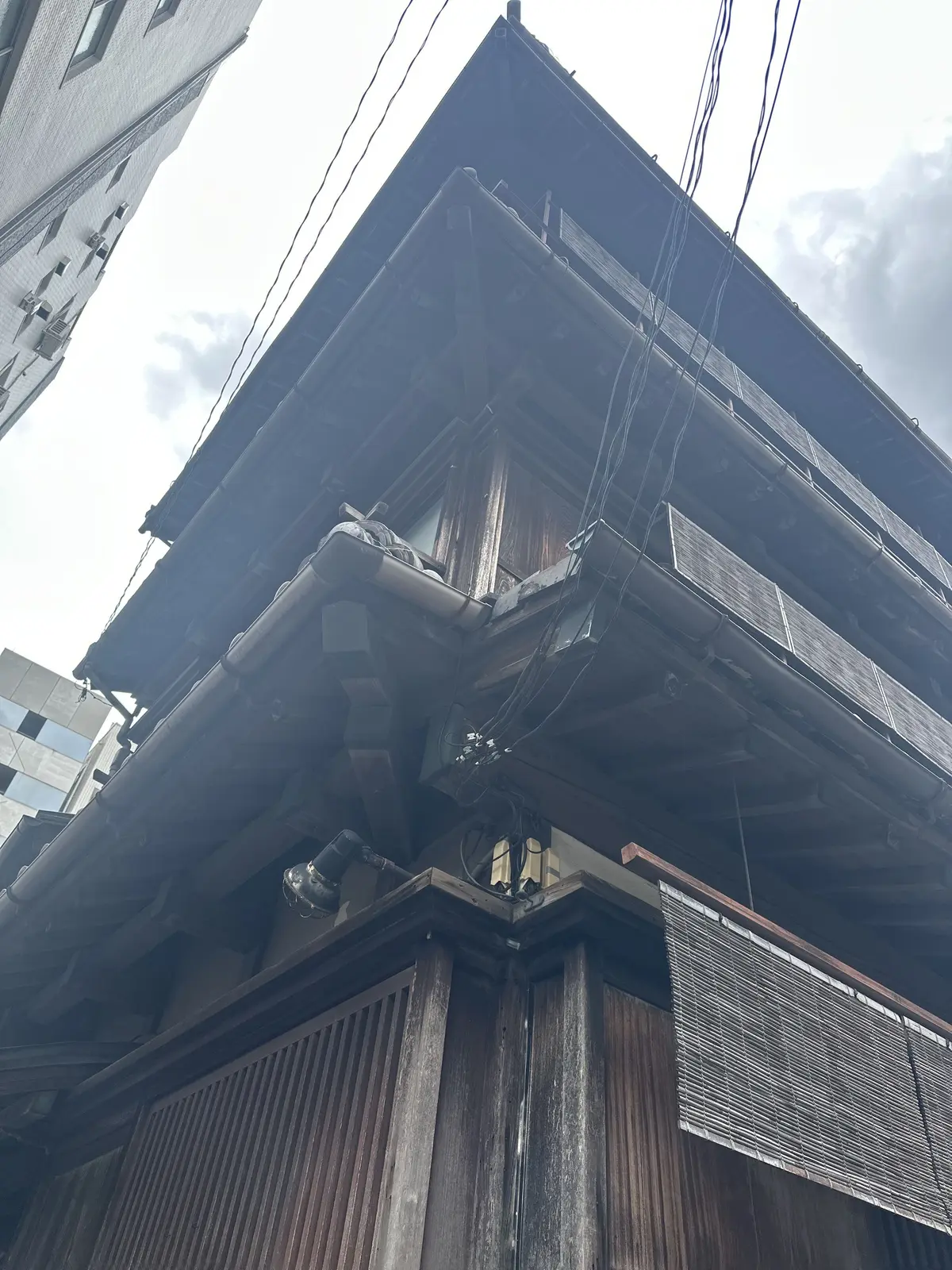 木造建築の伝統的な家屋の屋上部分で、木製の屋根やバルコニー、配管や電線が目立つ。