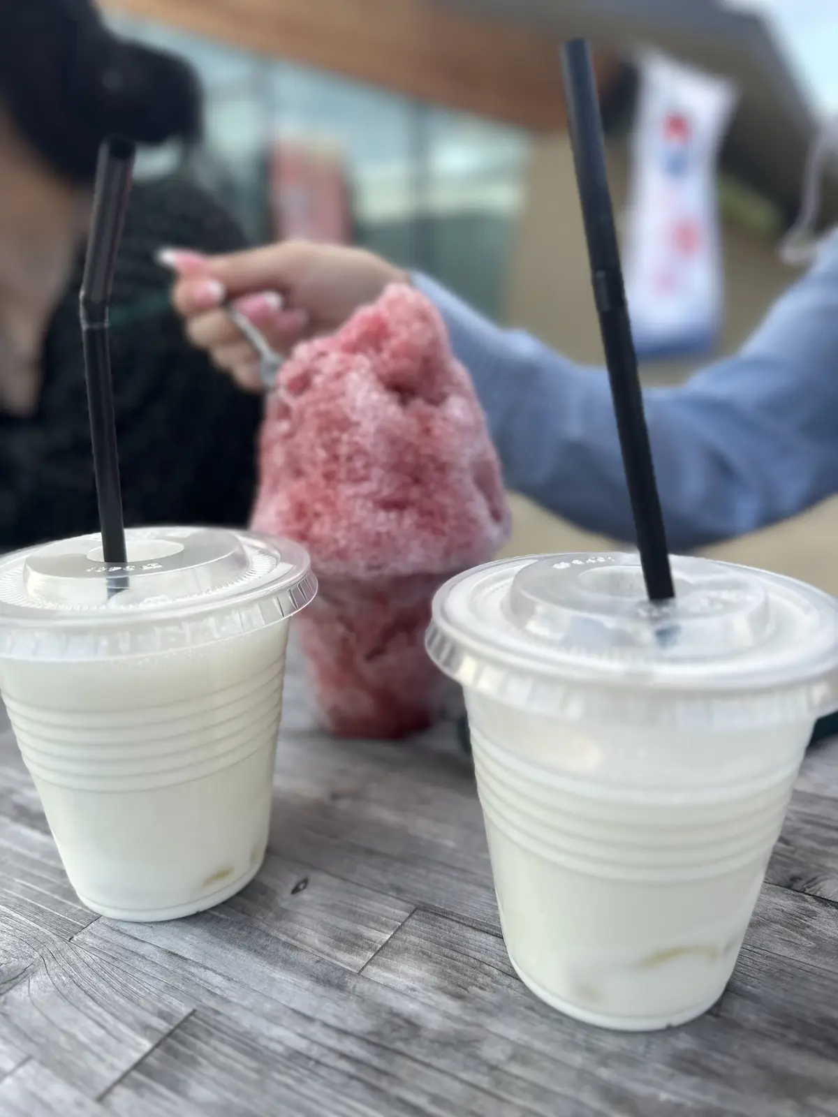 プラスチックカップに白いドリンクとピンクのシャーベットが並び、ストローが挿さっている