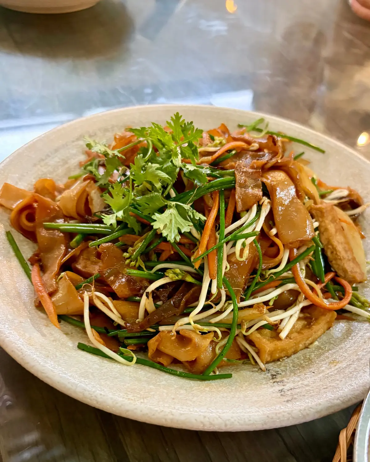 白い皿に、きくらげ、豆 sprouts、にんじん、緑の野菜がトッピングされた炒め物。