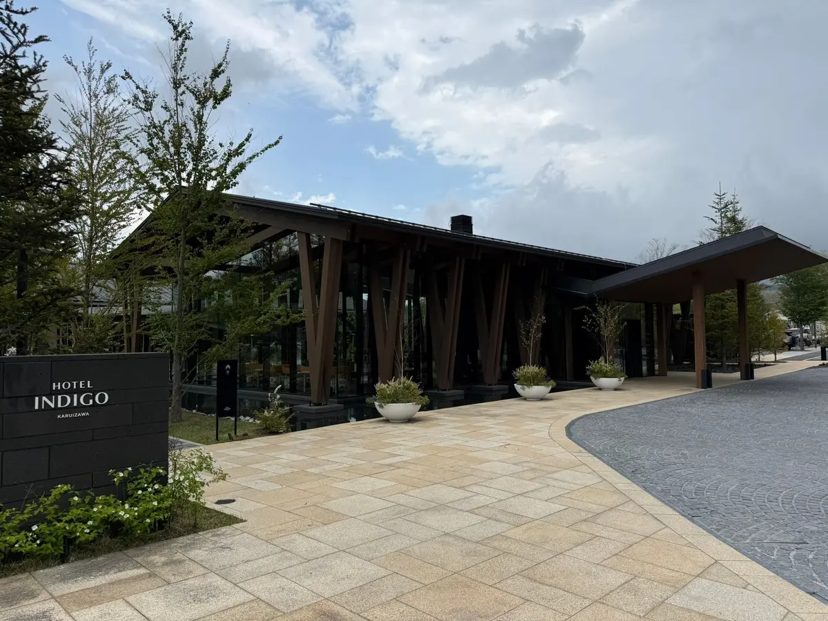 ホテルインディゴ軽井沢の入り口、モダンな建物と木製の柱、屋外のポットプランツが配置された石の通路