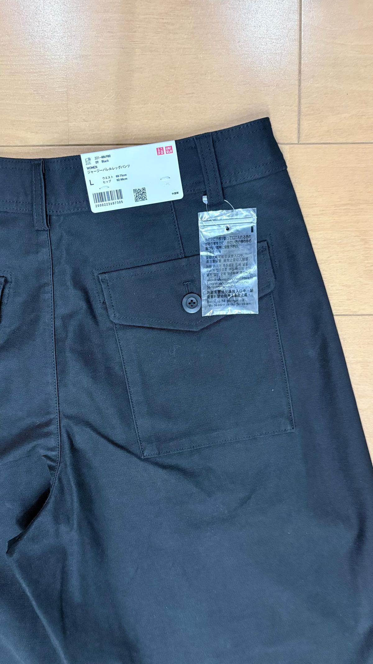 ユニクロの黒いパンツのバックポケット部分。左ポケットには白いタグが、右ポケットには小さな洗濯表示タグが付いている。サイズはL。