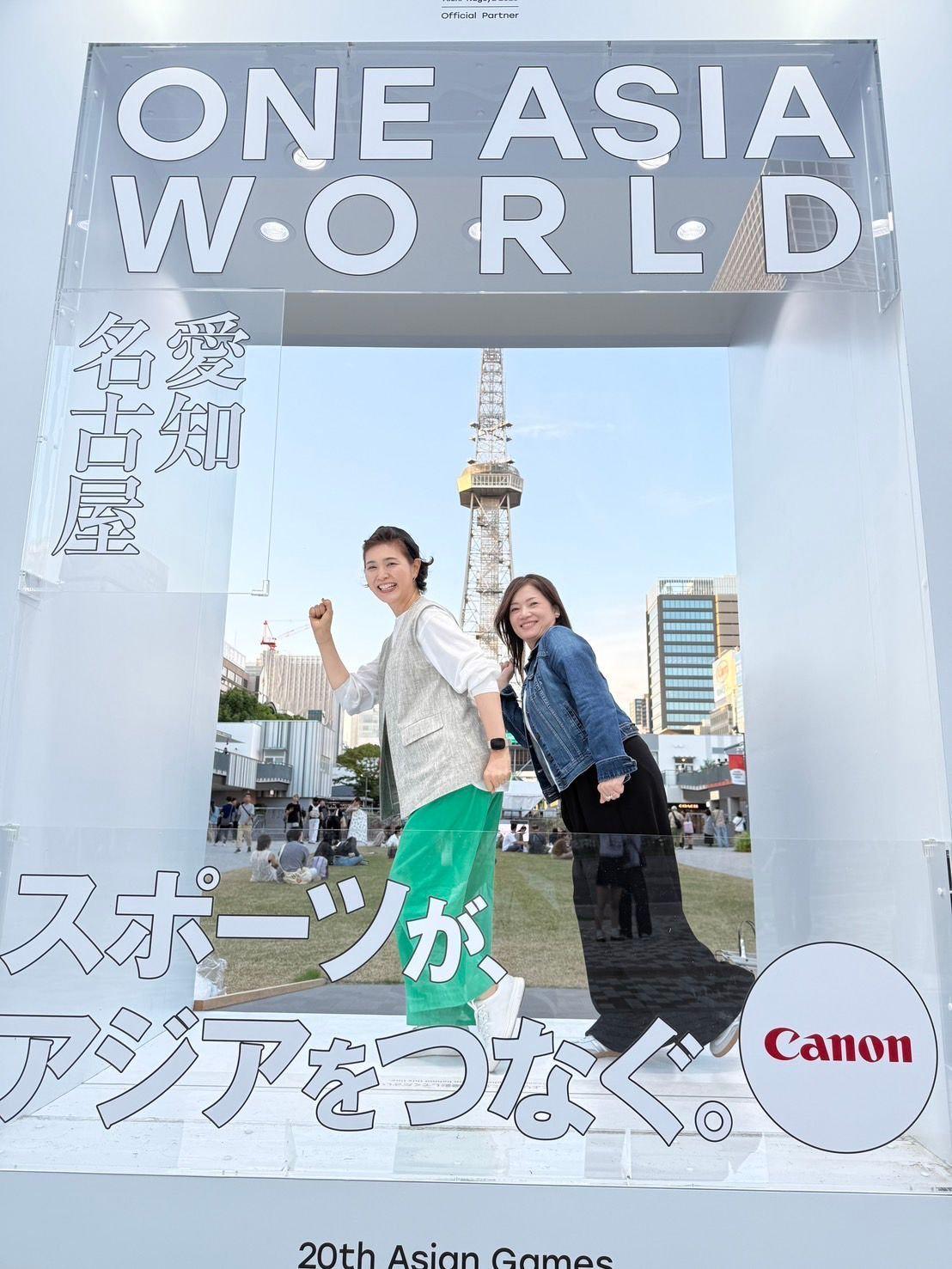 東京スカイツリーを背景に、芝生広場に人々が集まっている様子。周辺には高層ビル群が並び、晴れた空には雲が浮かんでいる。