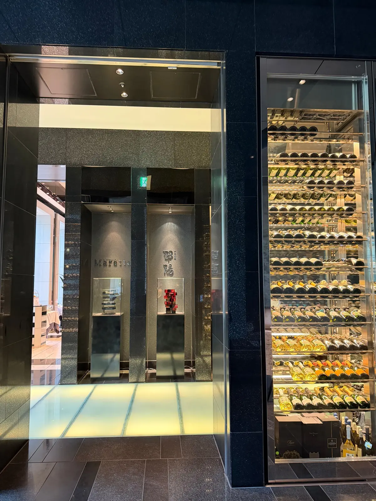 ガラスのショーケースに多数のワインが並び、店内には展示されたワインと装飾品が置かれている。