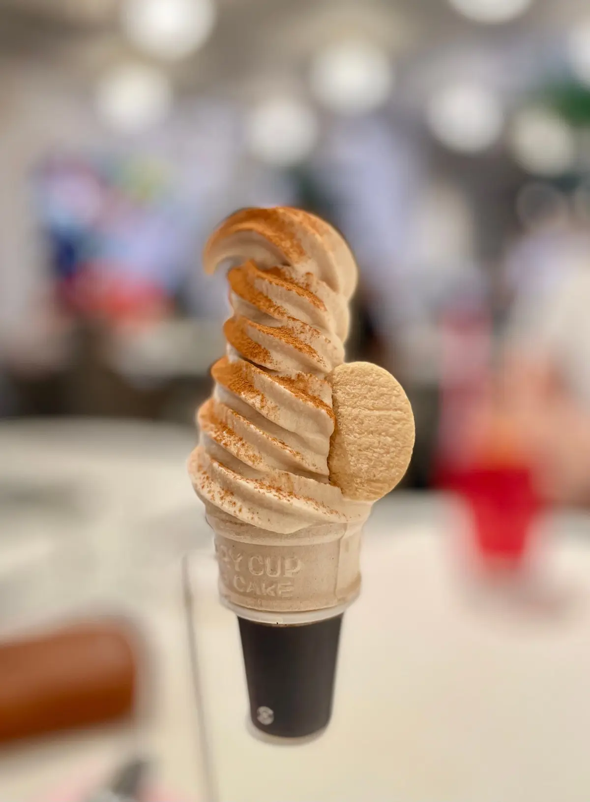 コーヒーアイスクリームのワフルのカップに、らせん状に積み重ねられたアイスクリームと、茶色の粉をふりかけたワフルが乗っている