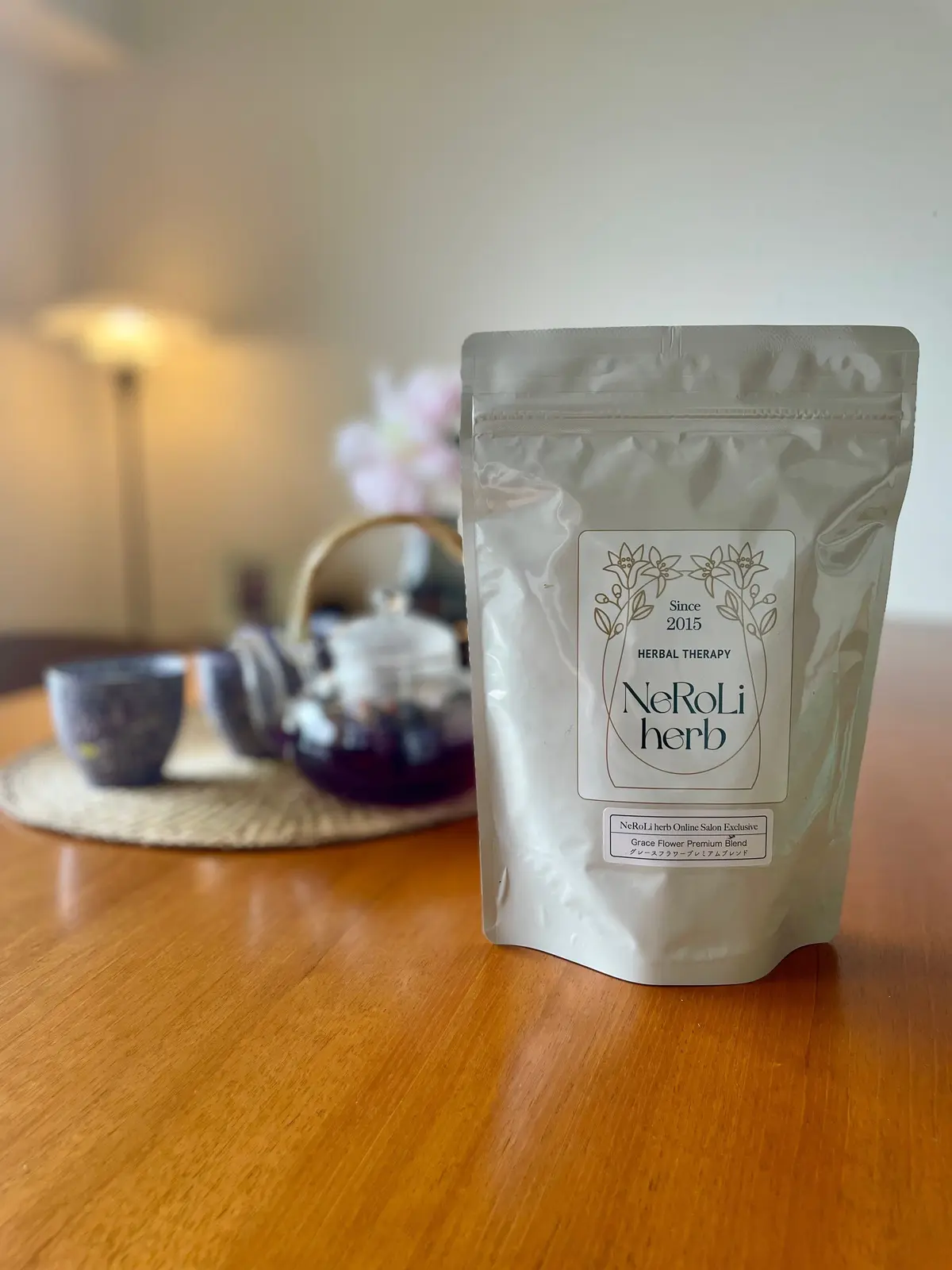 「NeRoLi Herb」のハーブティー袋が木製テーブルに置かれている。背景には茶碗とティーポットが並ぶ。