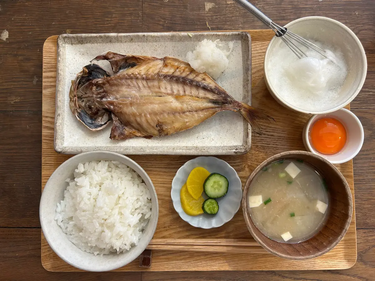 ランチメニュー　ヨリドコロ鎌倉のメニュー。木製のまな板に盛り付けられた和食。焼き魚、白米、味噌汁、卵、おろし和え、柑橘のスライス。