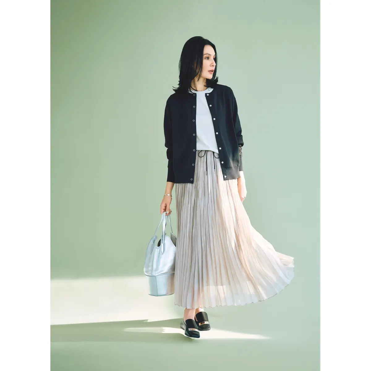 黒スナップボタンカーディガンに白トップスとアイボリープリーツスカートを合わせたコーディネート　モデル・田沢美亜
