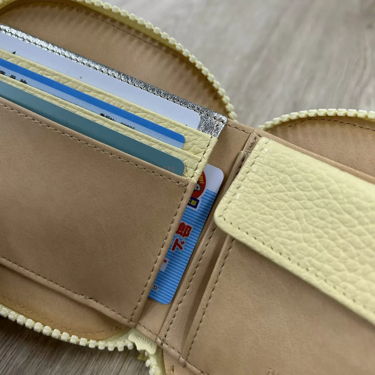 黄色の合皮製のカードケース。複数のカードスロットがあり、中にはクレジットカードやプラスチック製のカードが挿入されている。右側のポケットには、赤と白の日本の交通系ICカードが見える。