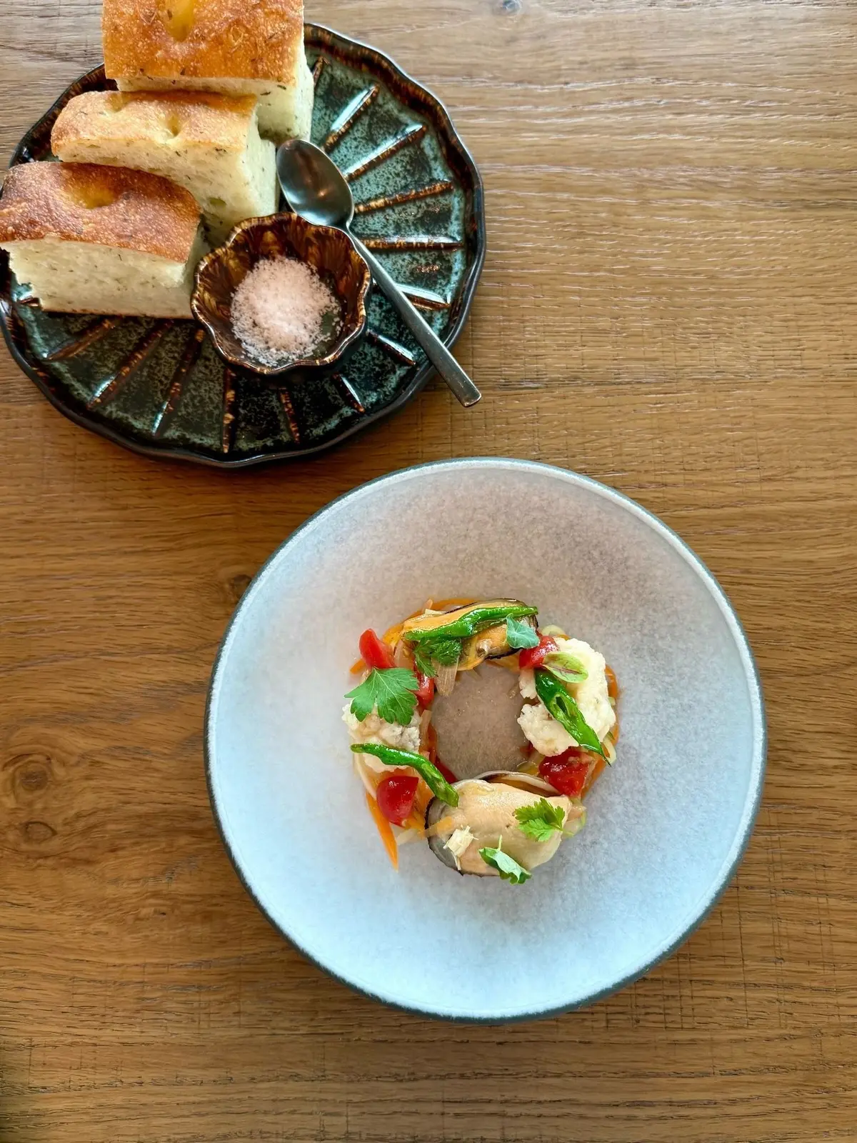 １Hotel Tokyo ３８階　レストラン「NiNi」、緑のプレートにパンと塩の小皿、灰色のお皿に野菜と魚の料理が並ぶ