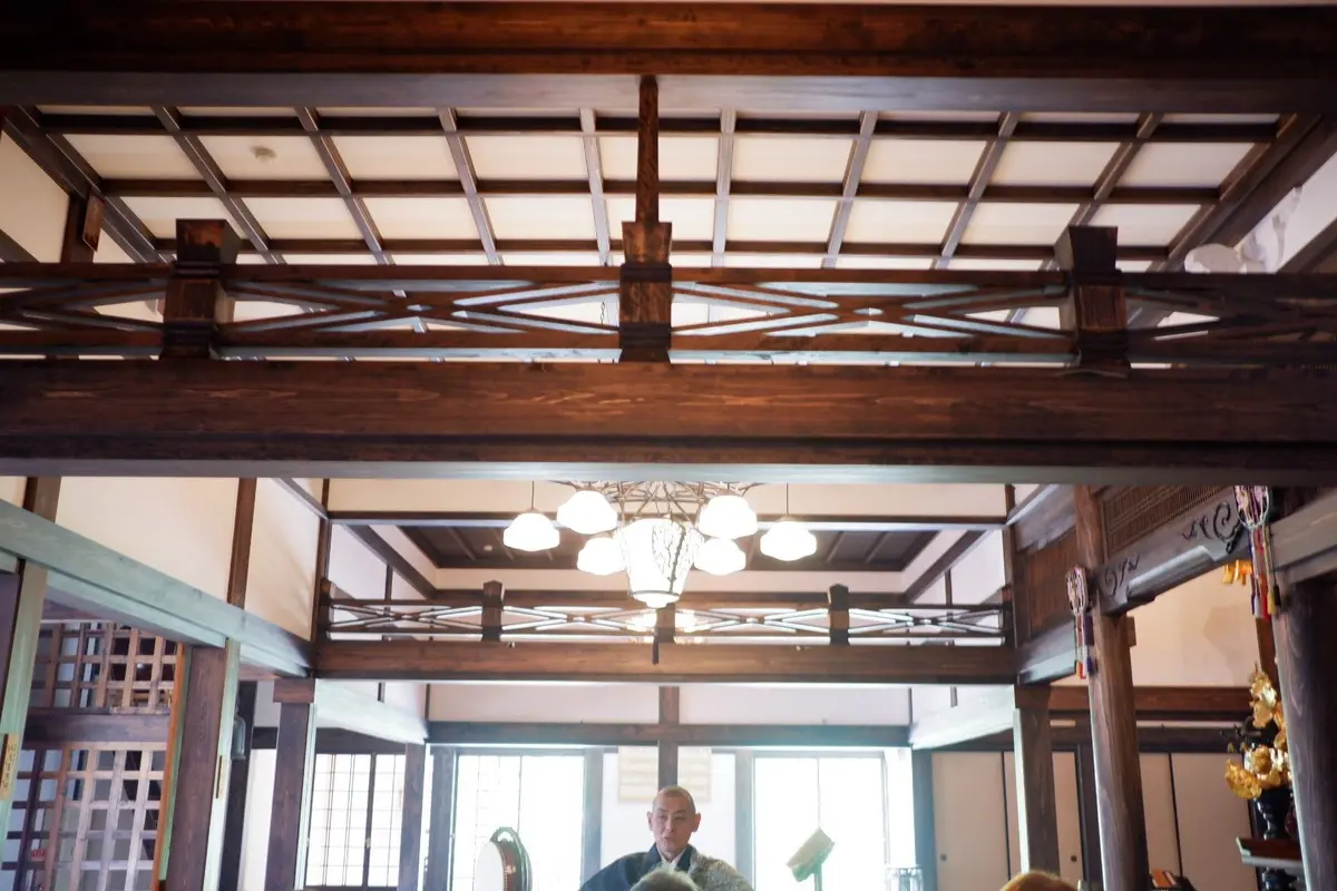 木造の天井と欄干のある伝統的な建物の内装で、中央に多灯の照明が吊るされている