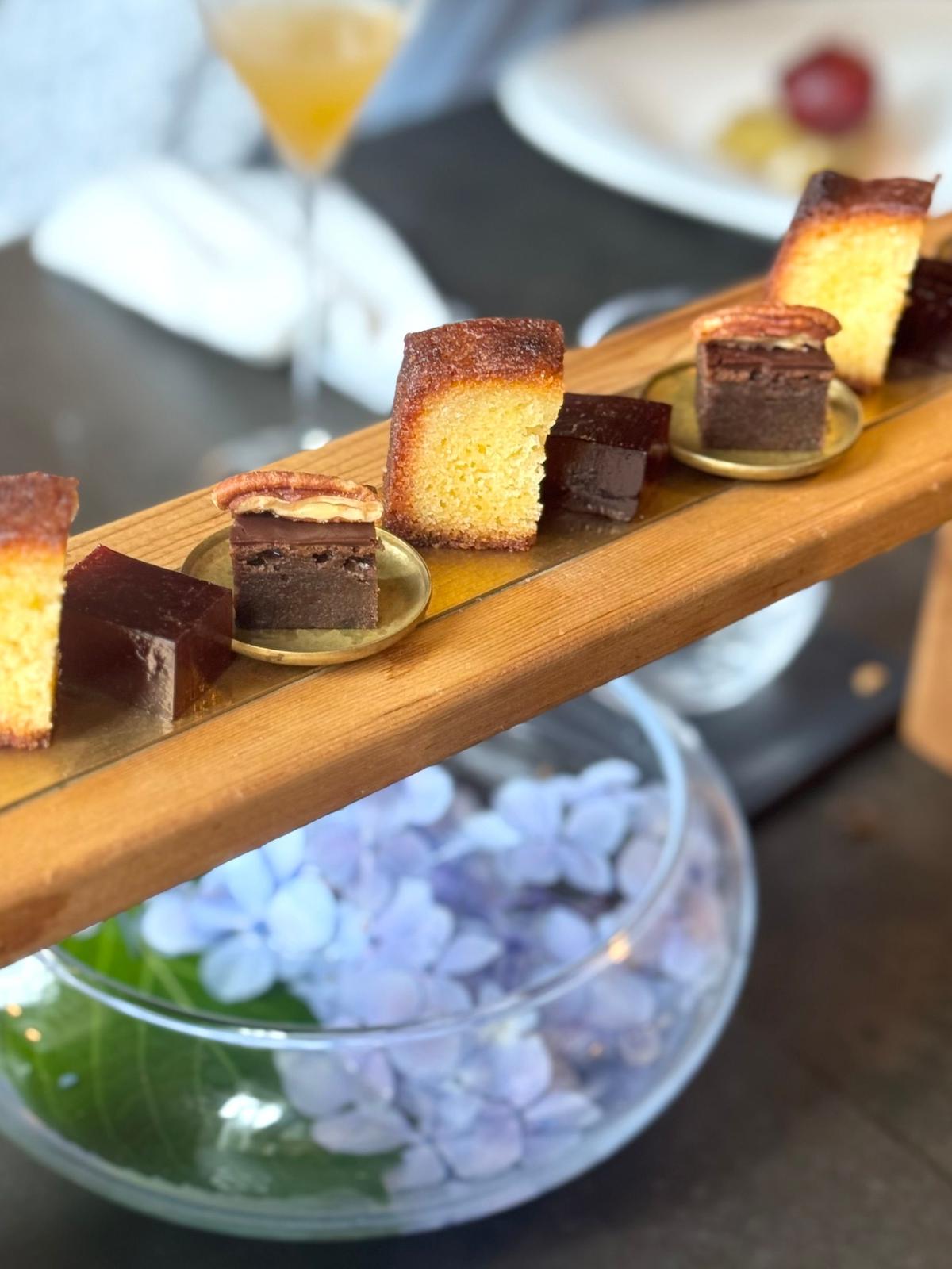 木製トレイに並べられたチョコレートケーキ、チーズケーキ、スポンジケーキなど多様なデザートの盛り合わせ