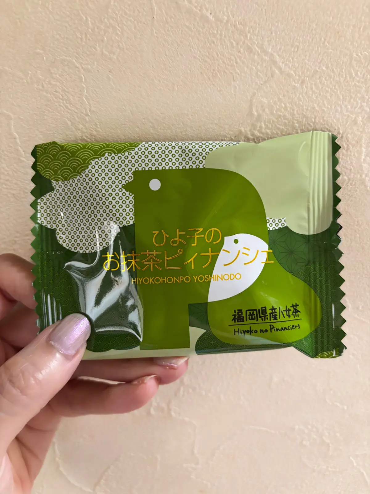 緑とピンクの包装紙に包まれた、お菓子の個包装が複数ある。包装紙には、漢字とカタカナで「ひよこのお抹茶ピナシエ」の文字が印刷されている。