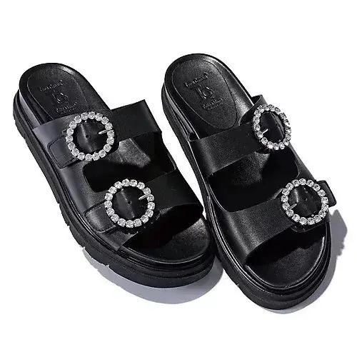 黒い2本ストラップの厚底サンダル。各ストラップに、白いストーンがあしらわれた丸い装飾が2つずつ配置されている。IGのロゴマークが刻印されている。
