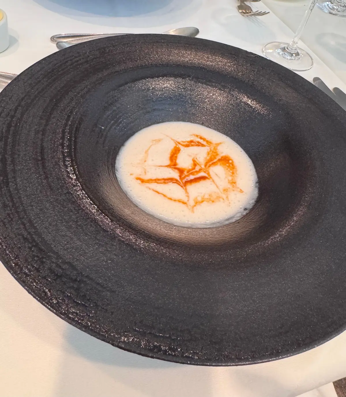 黒い丸い皿に白いクリームとオレンジの星型模様が乗った料理