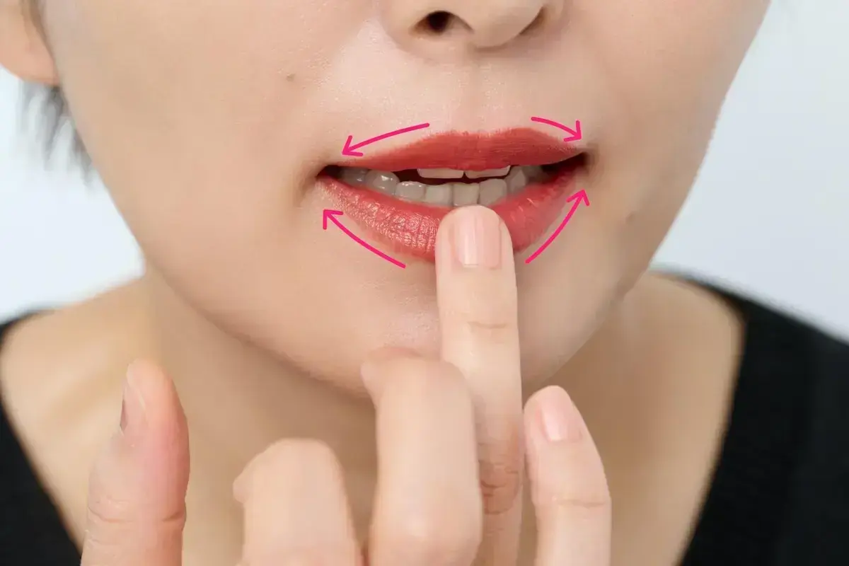 上下の唇の中央に塗ったリップカラーを、指で口角に向けてぼかします