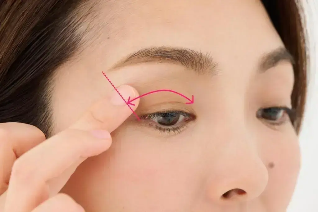 影色ブラウンのアイシャドウを中指に取って、アイホール（眼球の境目のくぼみ）にぼかします