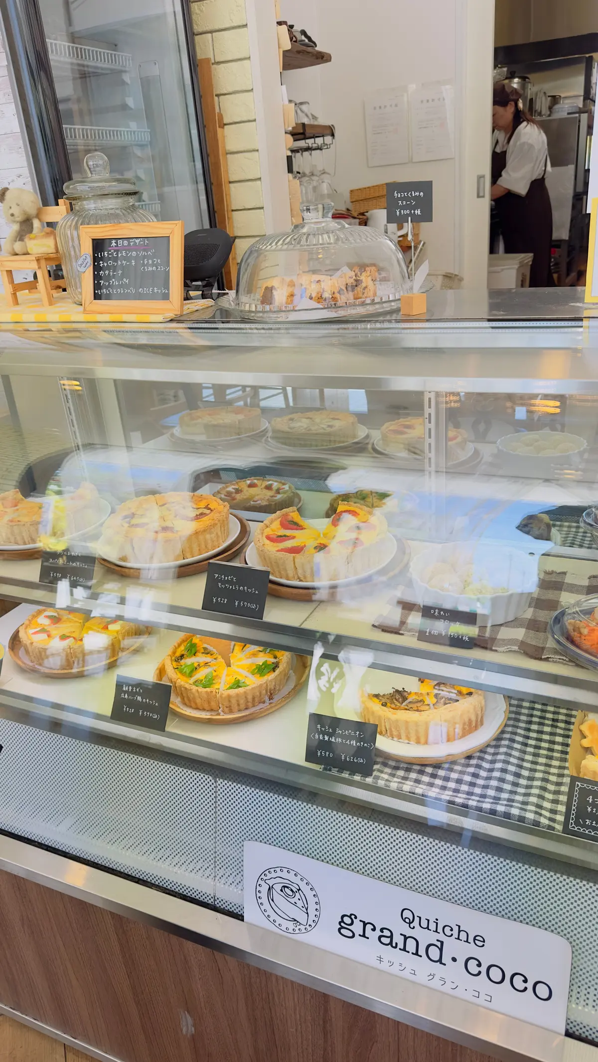 ガラスケースにさまざまなキッシュが並び、価格表示付きで店内には木製の棚やメニューが置かれている