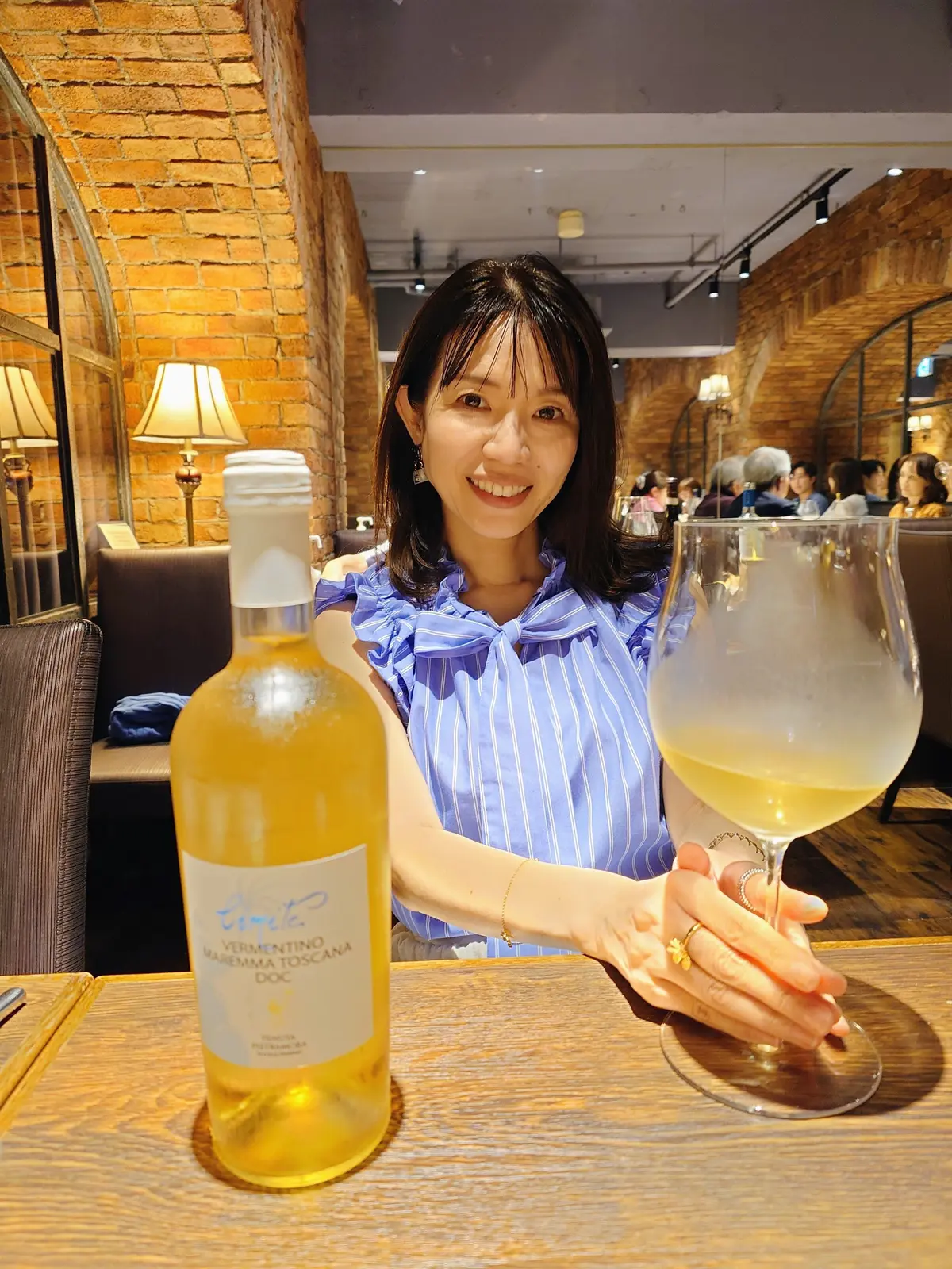 横浜のイタリアン「アクイロット」。テーブルには「LIMITE Vermentino Maremma Toscana DOC」と書かれたワインボトルが置かれている。背景にはレンガの壁と照明が映る。