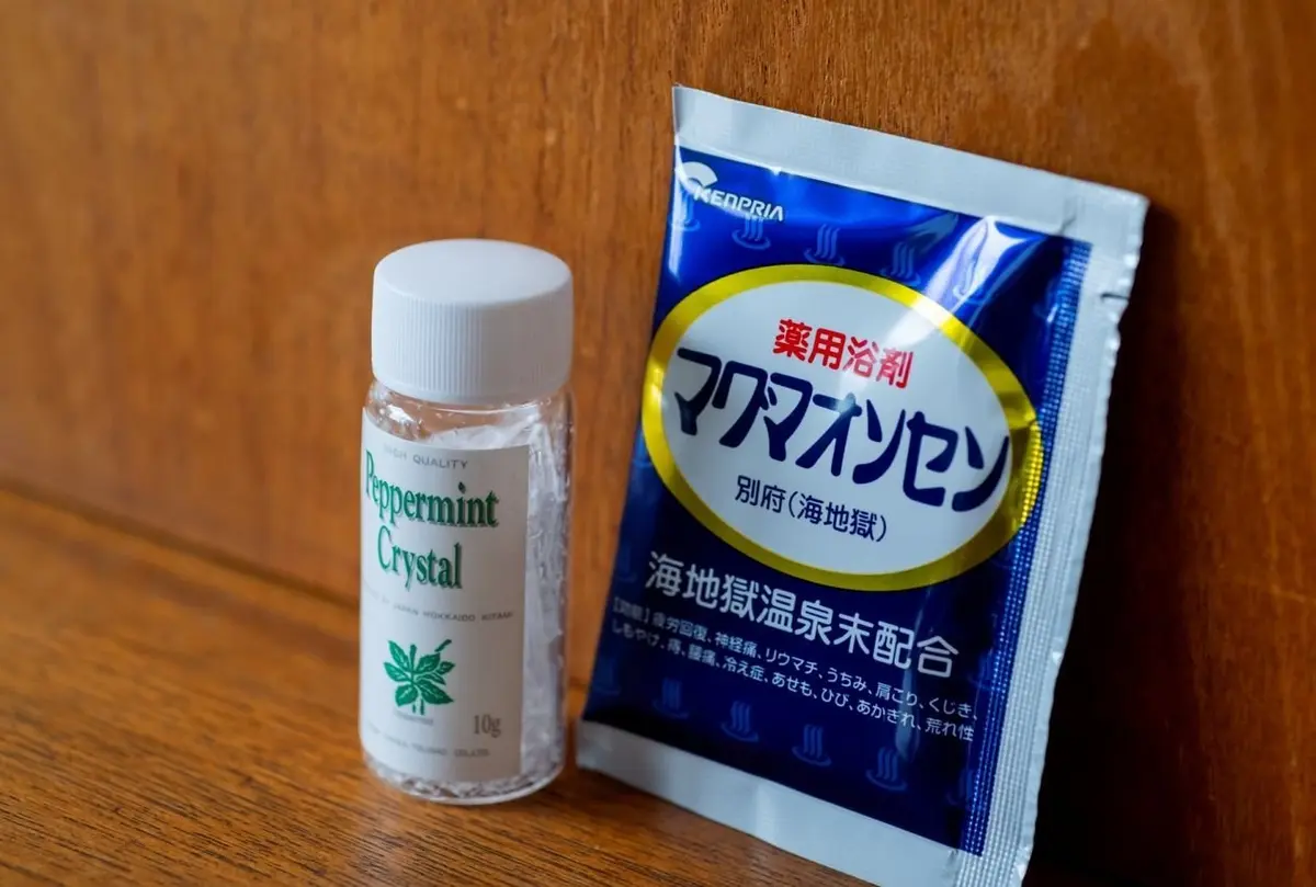ペパーミントの結晶と、メドプリアの入浴剤の個包装パックが置かれている。結晶は透明な瓶に入り、入浴剤は青と黄色のパッケージ。