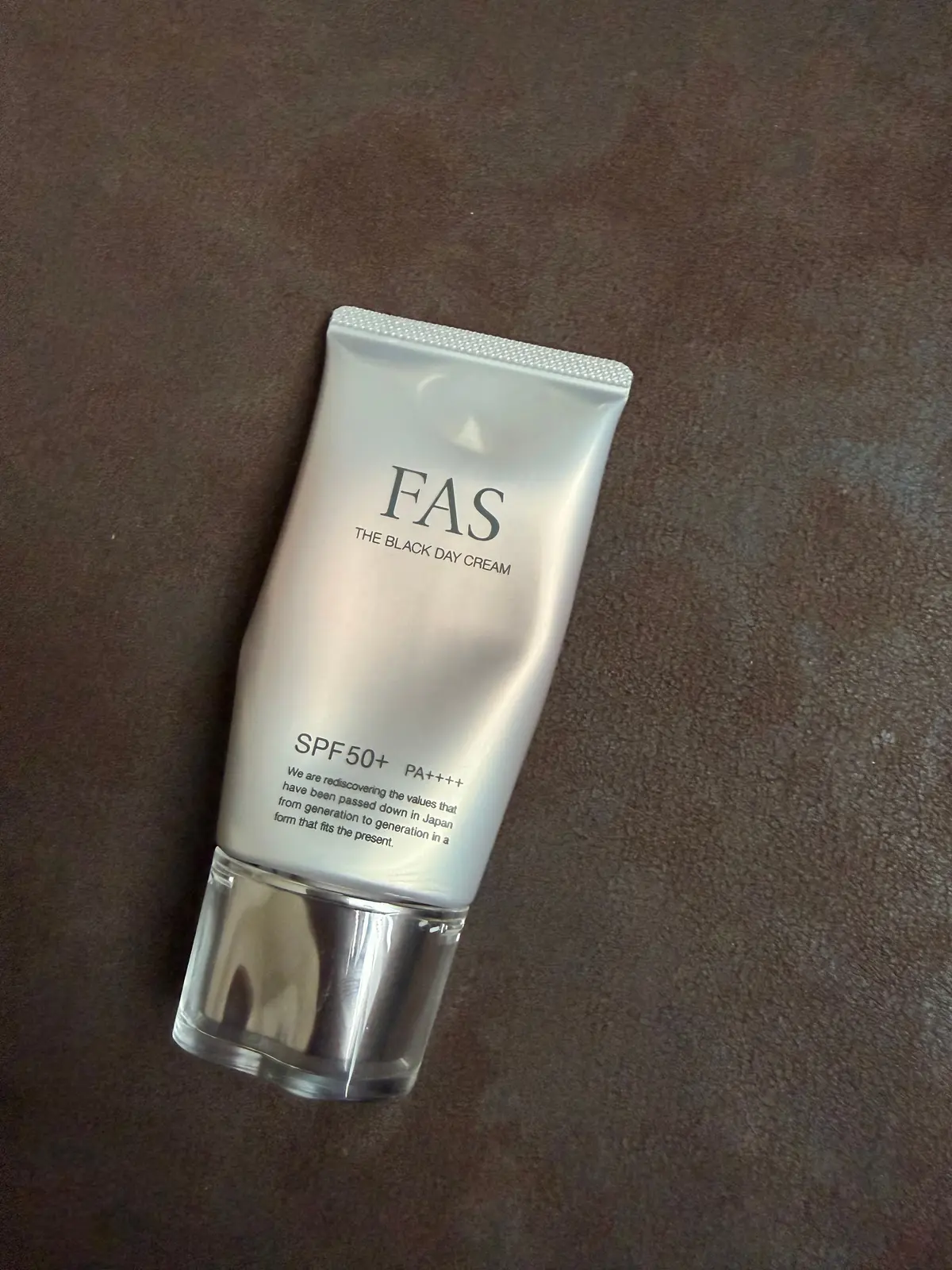 白いチューブ容器に「FAS THE BLACK DAY CREAM」と書かれた日焼け止めクリーム、SPF50+ PA++++と表示された製品が茶色の布の上に置かれている