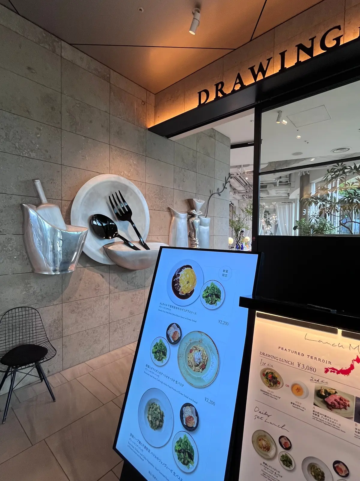 石の壁に置かれた食器とフォーク、ナイフ、スプーンが並び、メニューがディスプレイされたレストランのインテリア