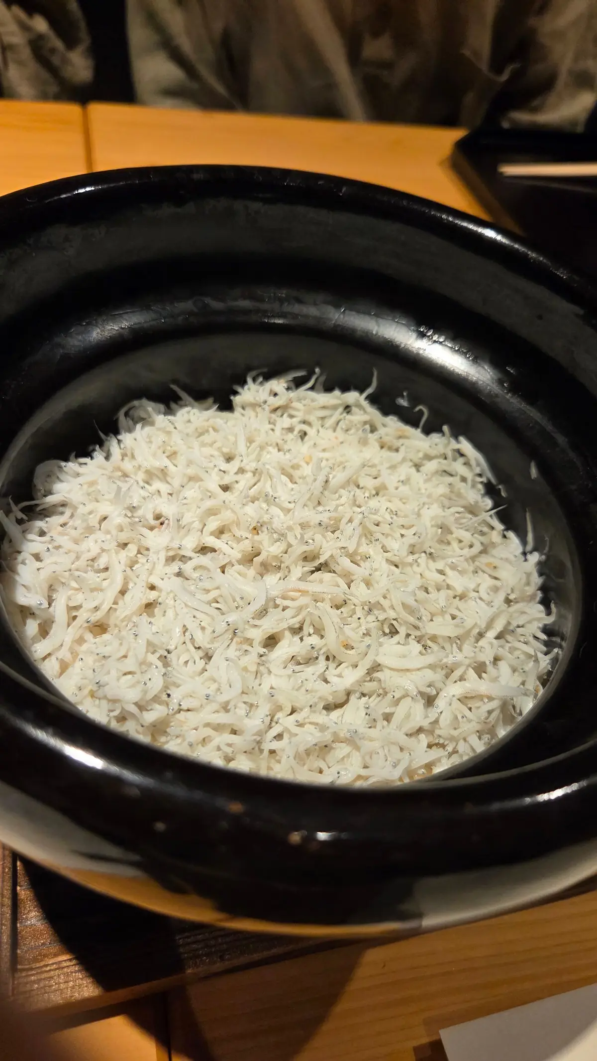 黒い陶器の鍋に入った、白い細長い麺類。表面にはクリーム状のソースが絡んでおり、全体的にふんわりとした印象。