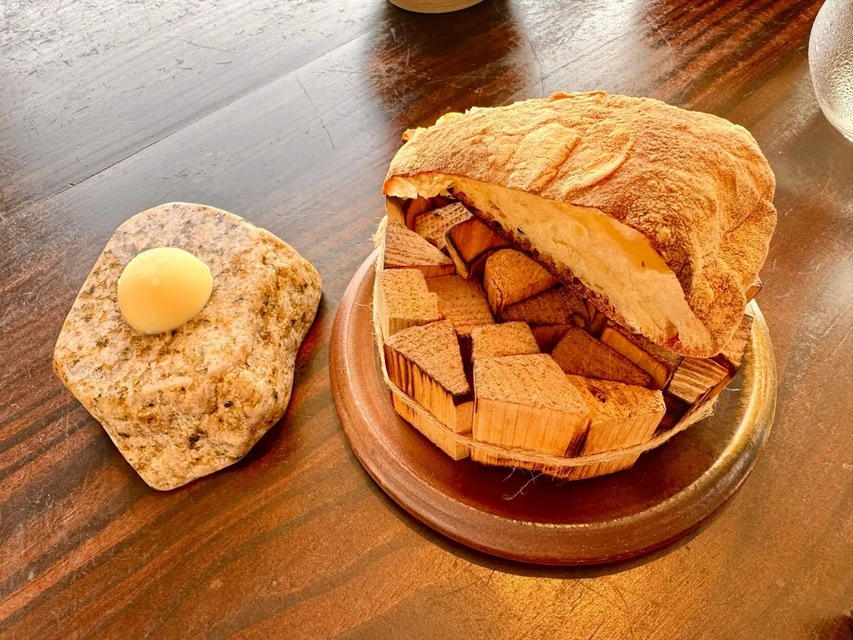 木製テーブルに、切られたリンゴとバターを乗せたパンが置かれている