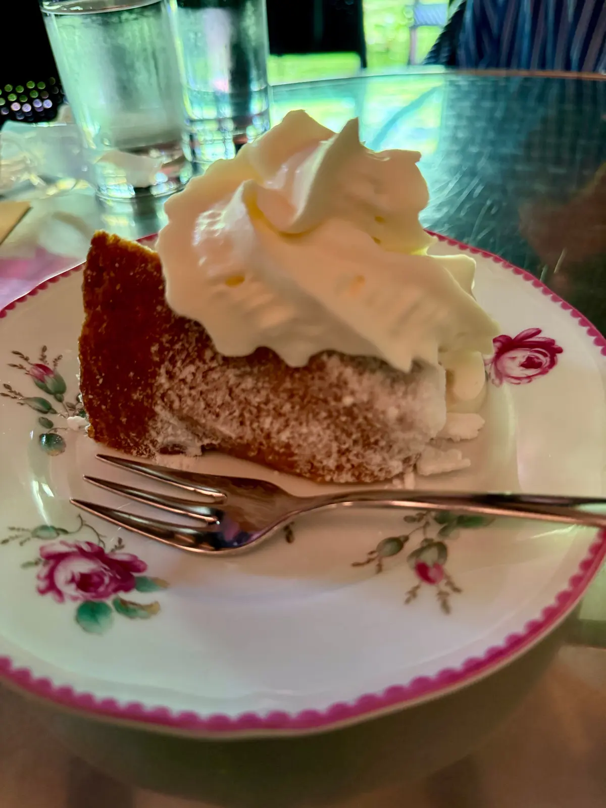 花柄のプレートに、クリームをトッピングしたスライスしたケーキとフォークが置かれています。
