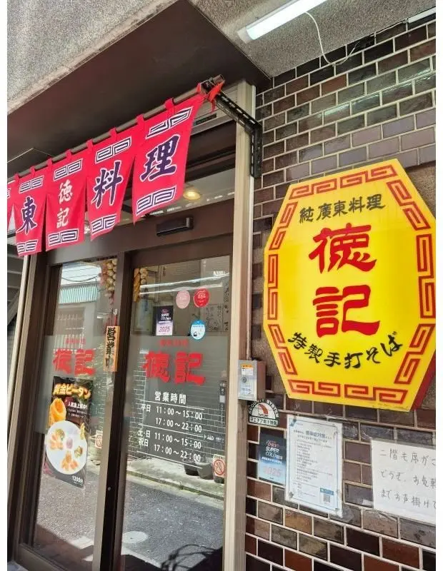 赤と黄色の看板が目立つ、日本のラーメン店「俺記」の店構え。窓にはメニューや営業時間などが掲示され、右側には大きなロゴが貼られている。
