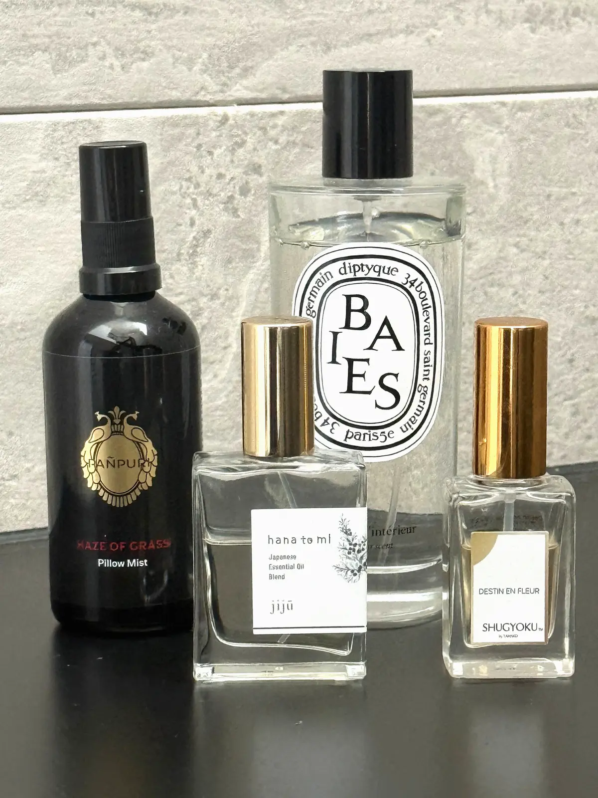 左から、HanpuriのHaze of Grassピローミスト、DiptyqueのBAIESキャンドル、jijüのhana to mlエッセンシャルオイル、ShugokuのDestin en Fleurの香水瓶が並ぶ様子。