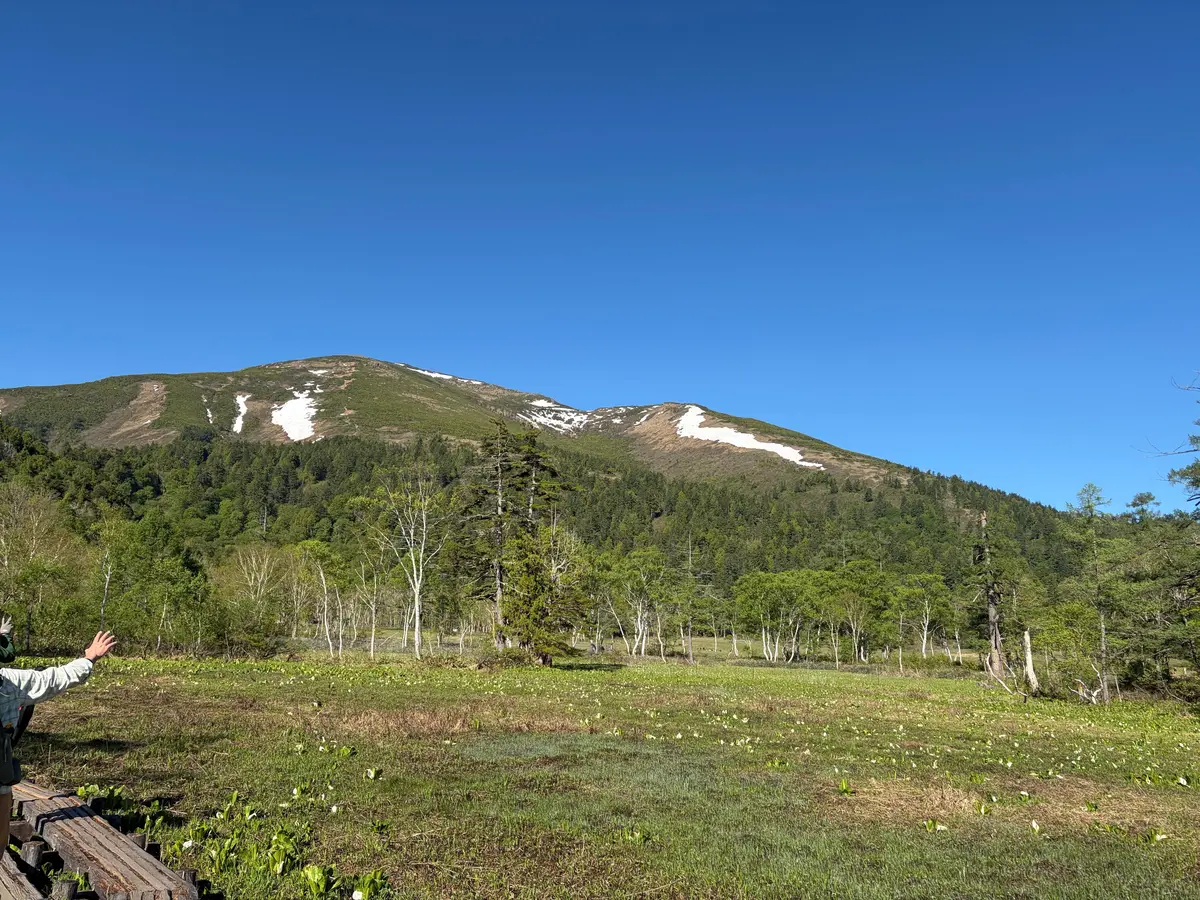 オゼ国立公園の看板前で、登山用リュックを背負った2人が笑顔で並んでいる